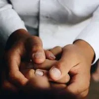 Two hands holding the hands of another person that is lying down Two hands holding the hands of another person that is lying down