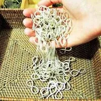 A hand full of small silver infinity signs spilling them into a woven basket A hand full of small silver infinity signs spilling them into a woven basket