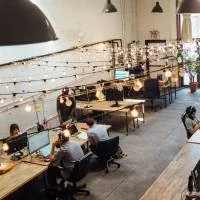 People working in a modern and cosy looking open plan office with high ceilings People working in a modern and cosy looking open plan office with high ceilings